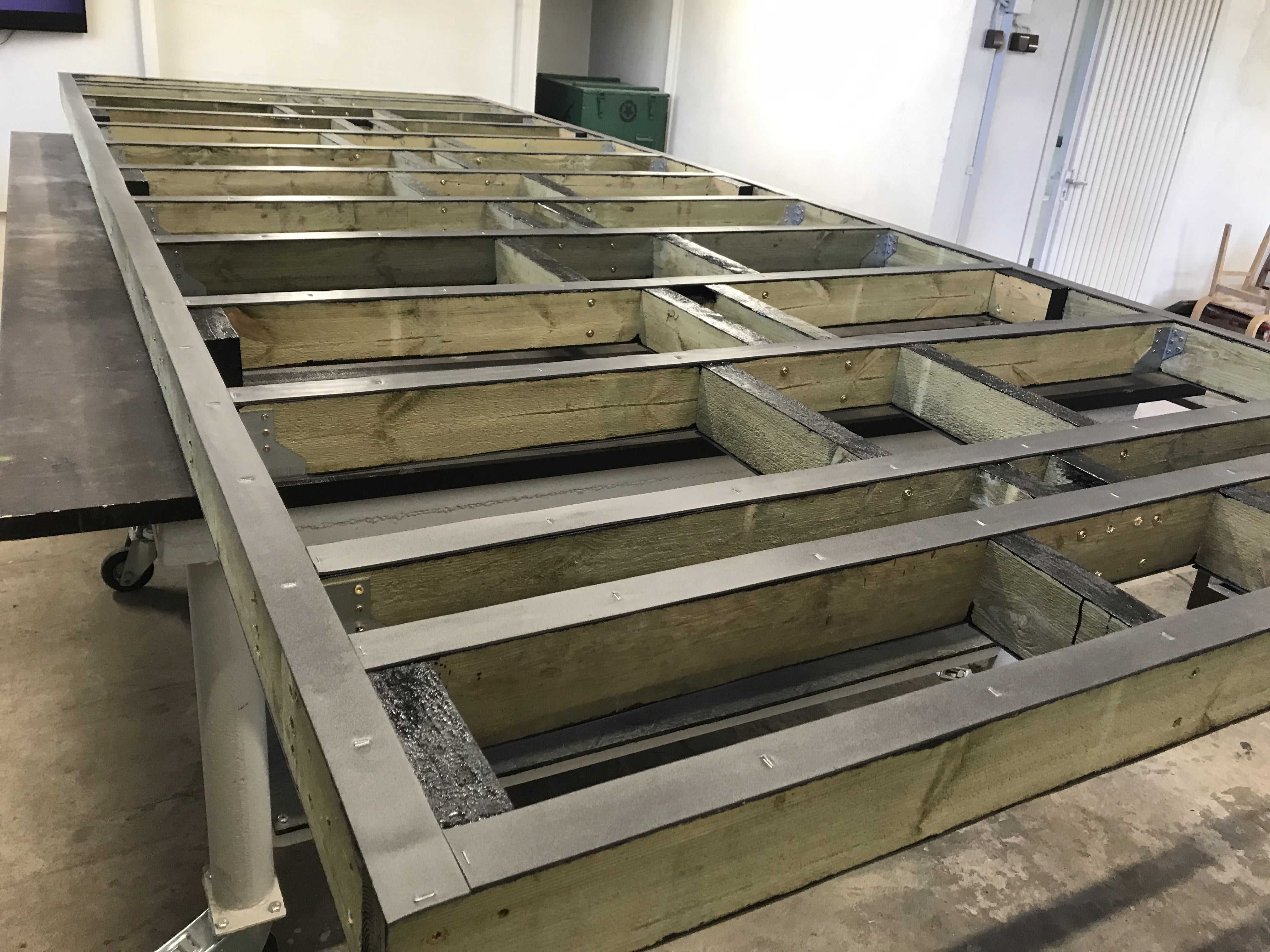 Wooden frame structure on a concrete floor with metal brackets