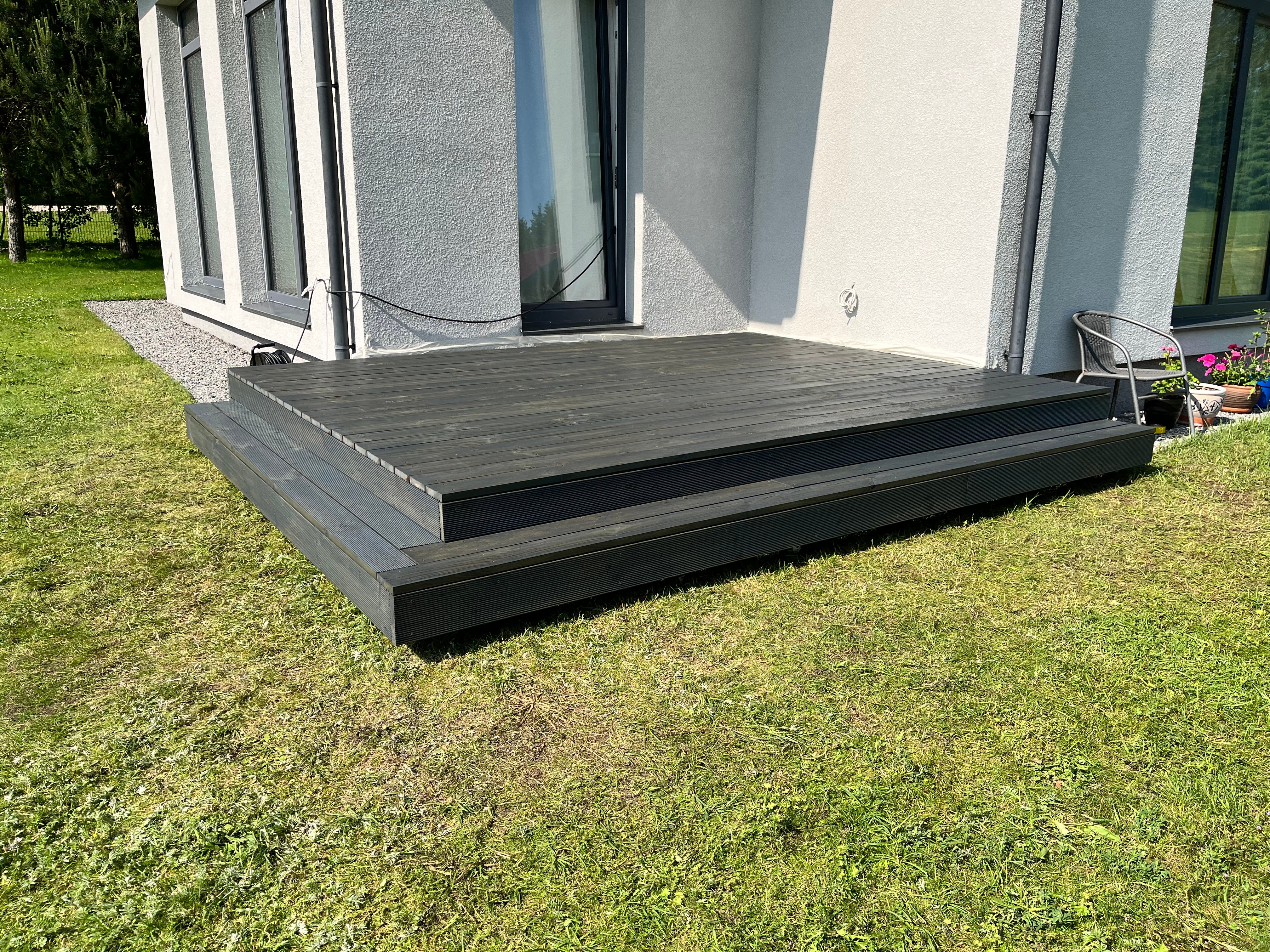 Modern house exterior with a gray deck and steps leading up to it.