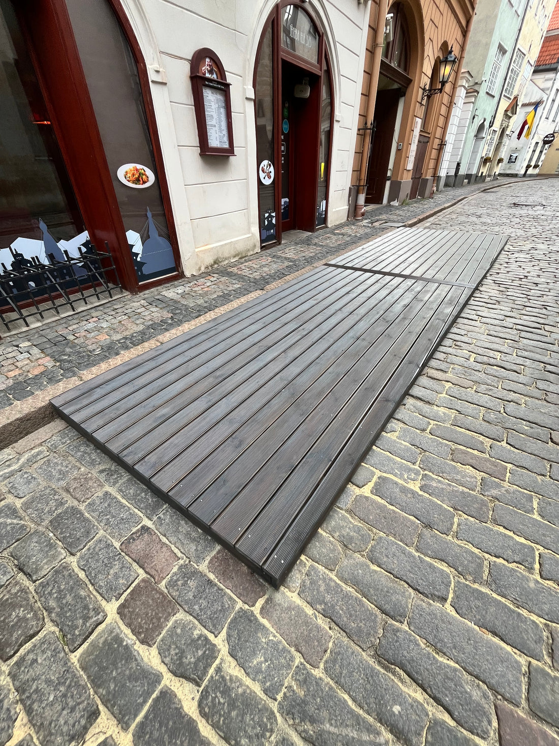 Wooden bench against a stone wall on a street with buildings in the background