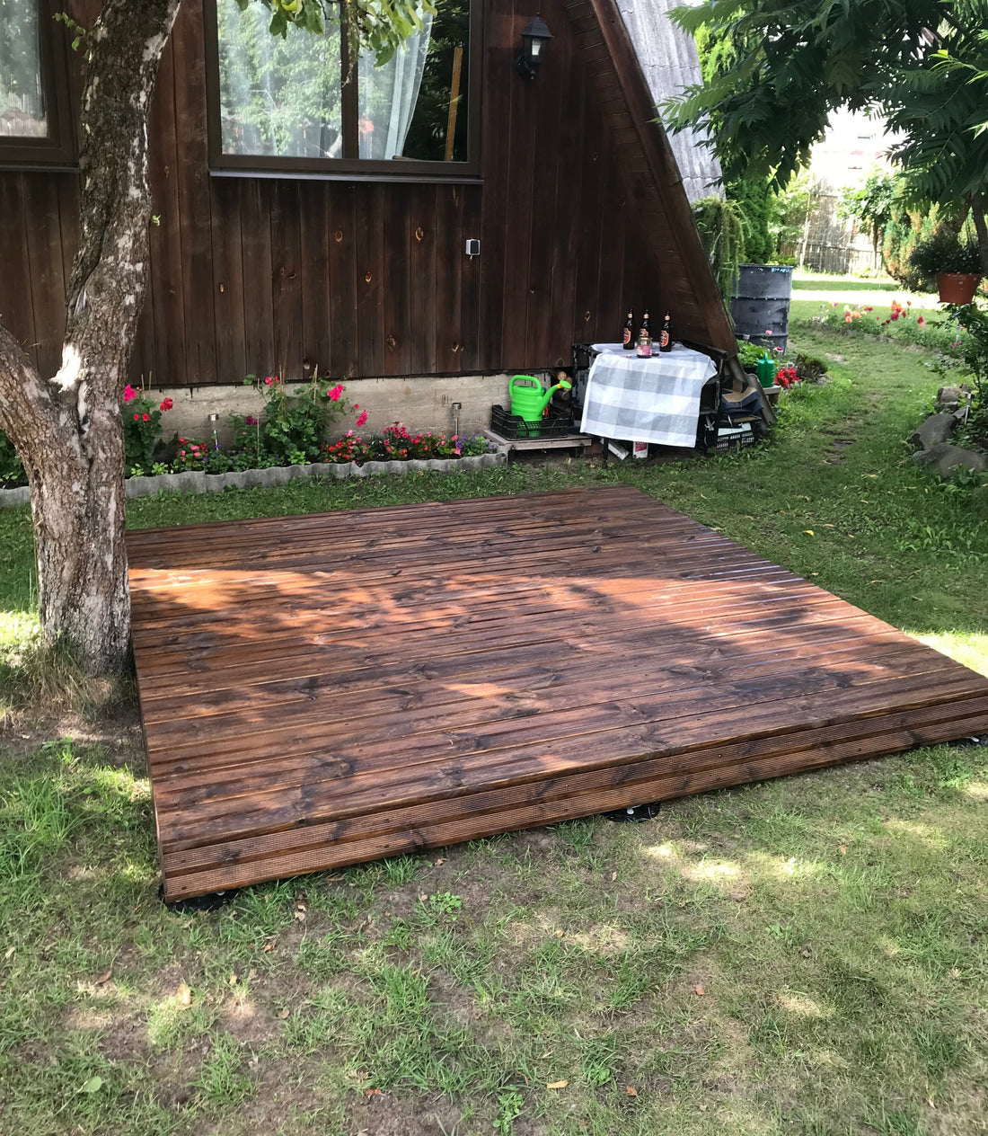 Wooden platform in a backyard with a cabin in the background
