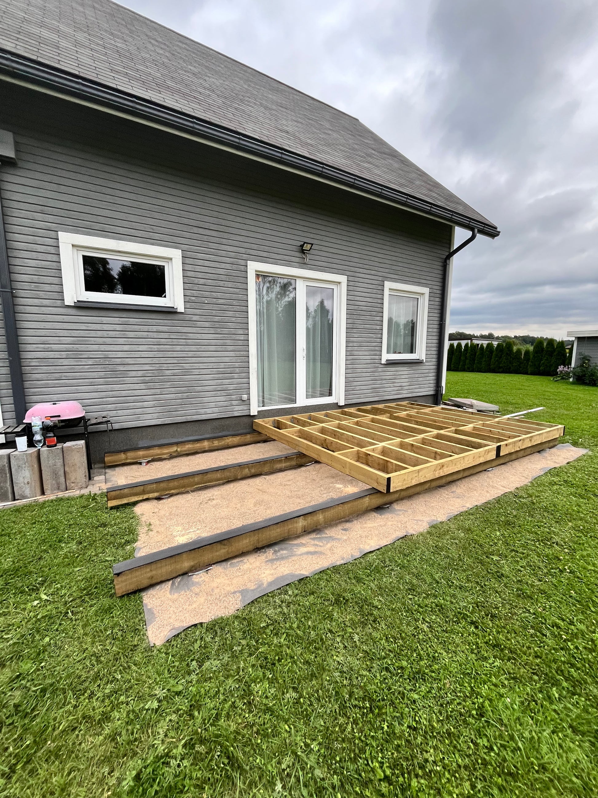House exterior with a new deck under construction on a grassy lawn.