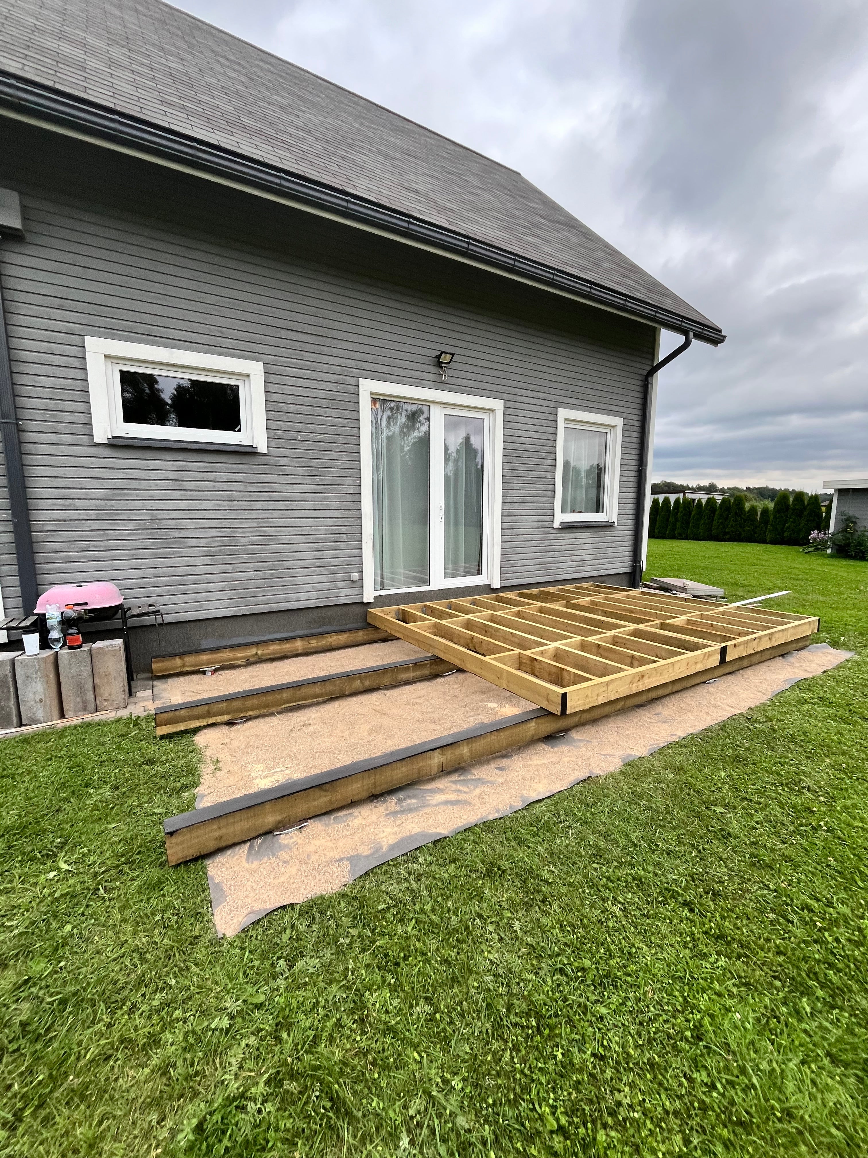 House exterior with a new deck under construction on a grassy lawn.