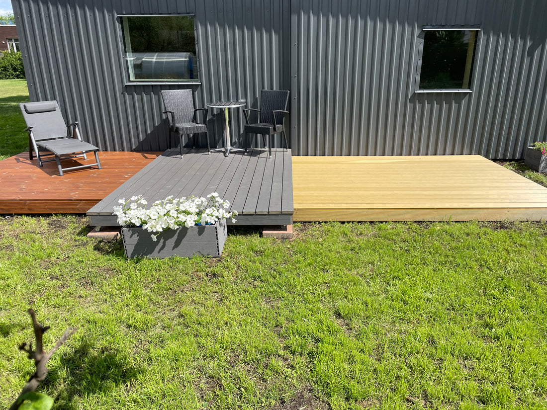 Wooden deck on grass with a corrugated metal wall in the background