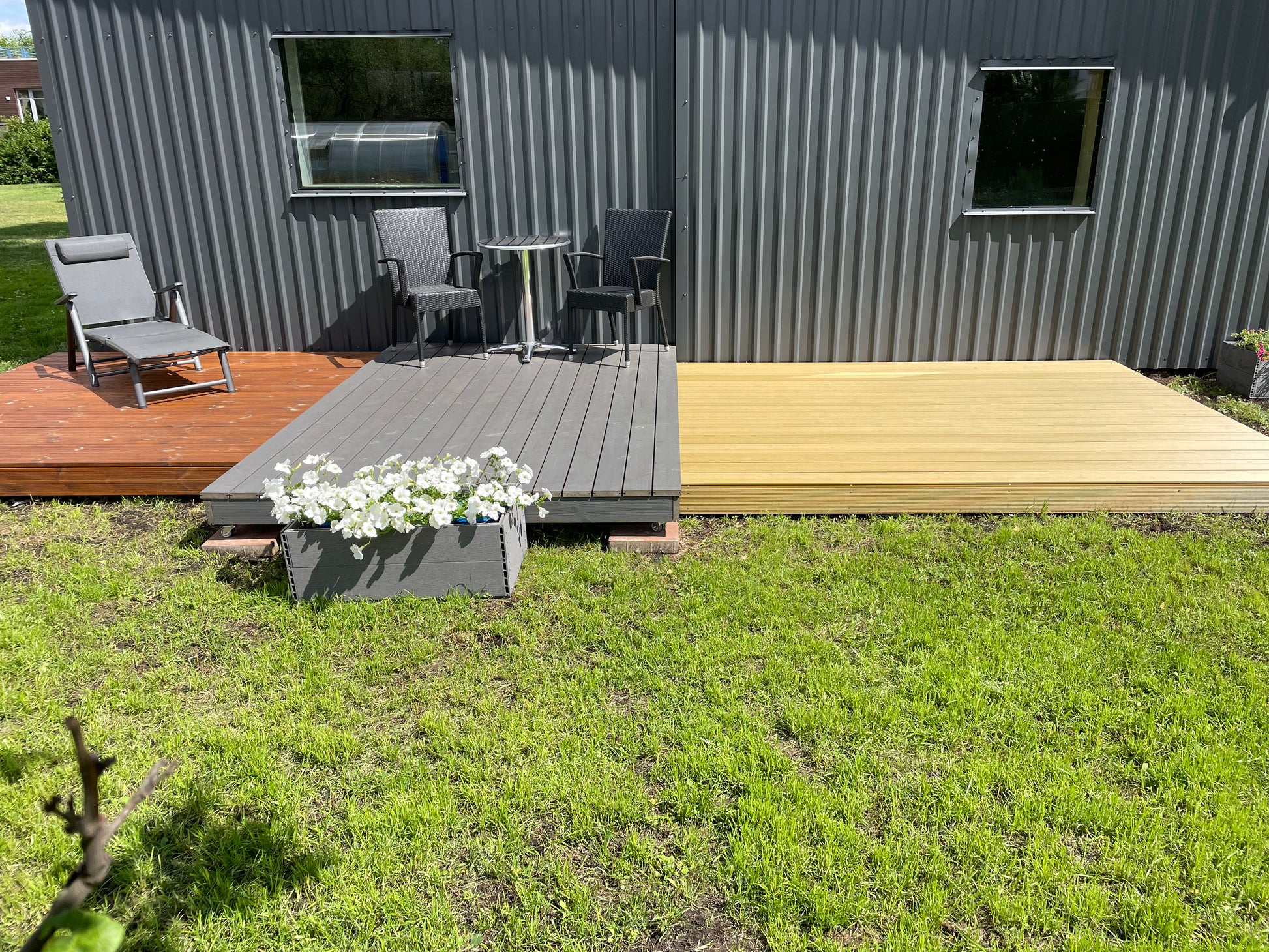 Small house with a deck and outdoor furniture on a grassy area
