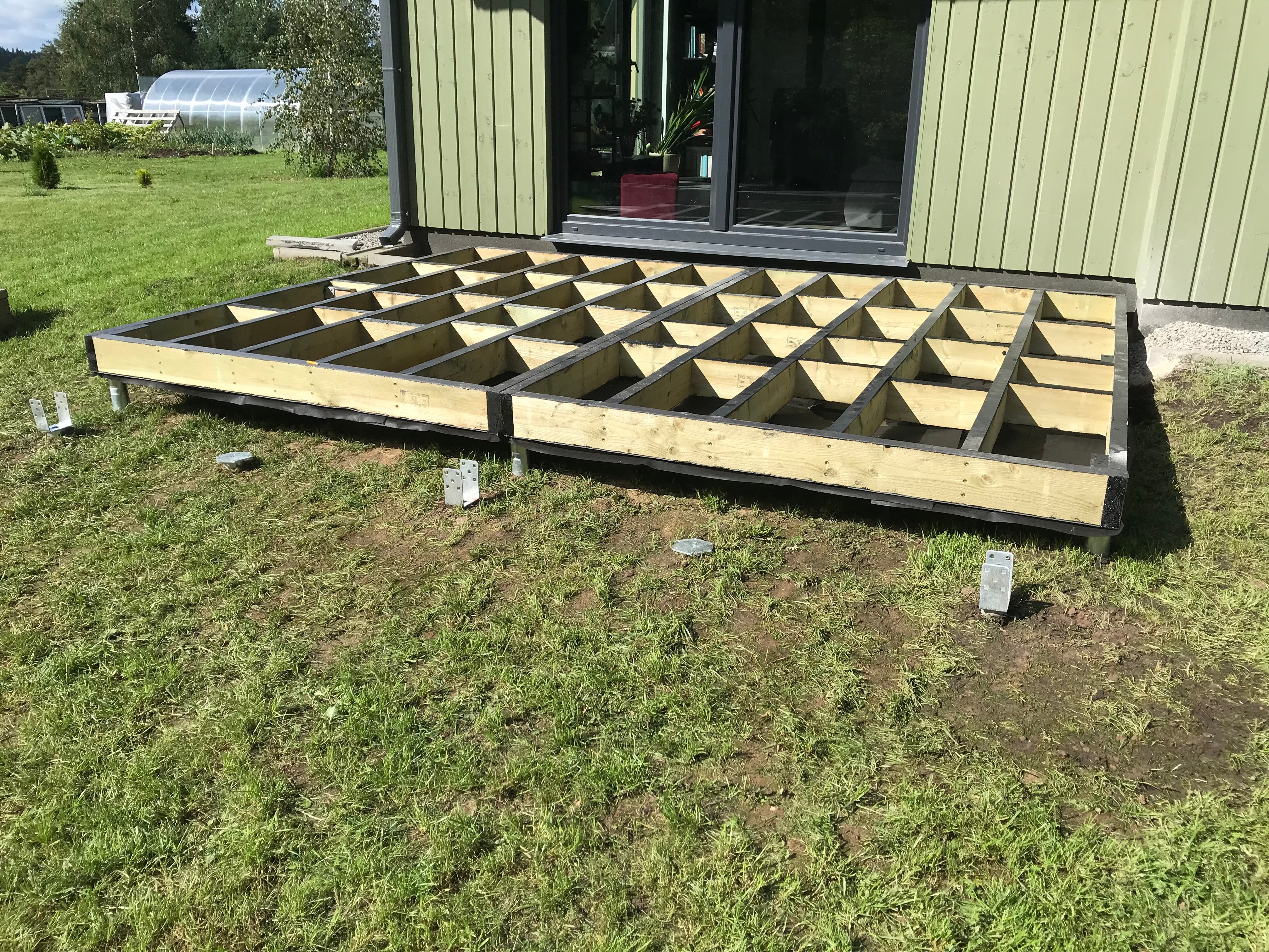 Wooden deck foundation in front of a building on a grassy area