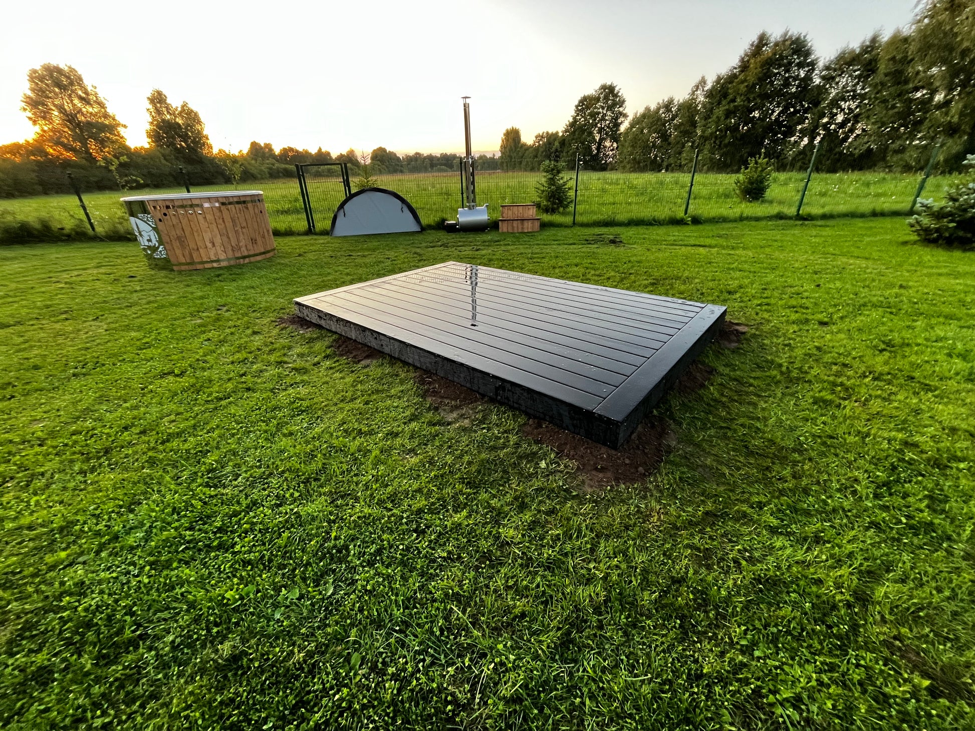Wooden platform in a grassy outdoor area with trees in the background