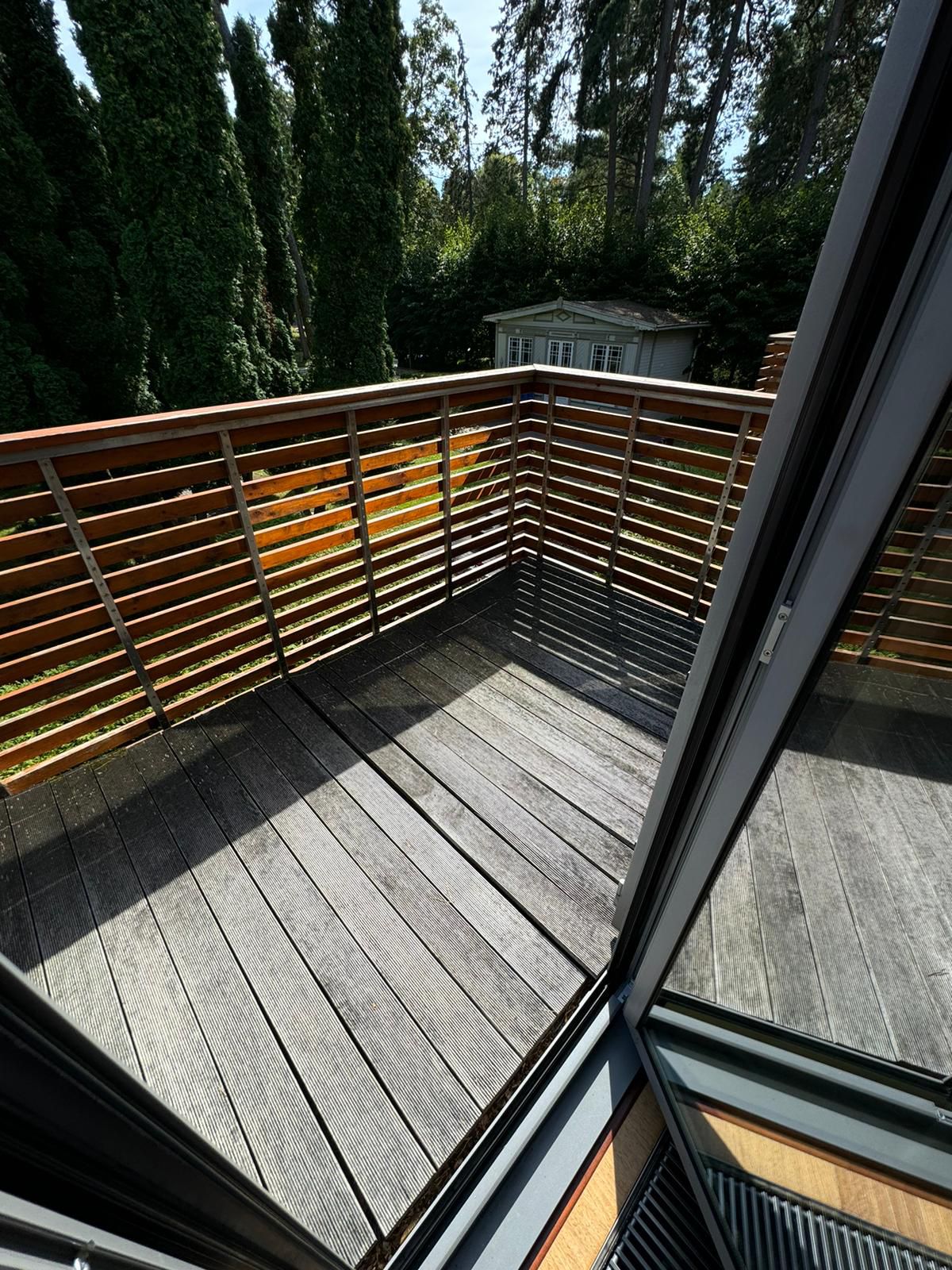 Wooden deck with railing and greenery in the background